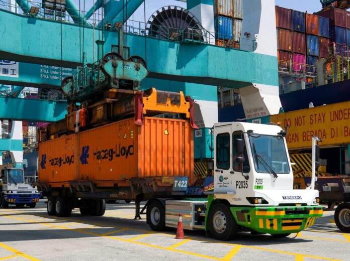 Electric prime mover on duty, carrying a Hapag-Lloyd container