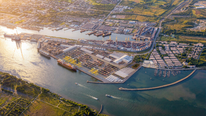 Aerial view of the Port of Klaipėda, showing container terminals, cargo vessels, cranes and surrounding industrial areas.